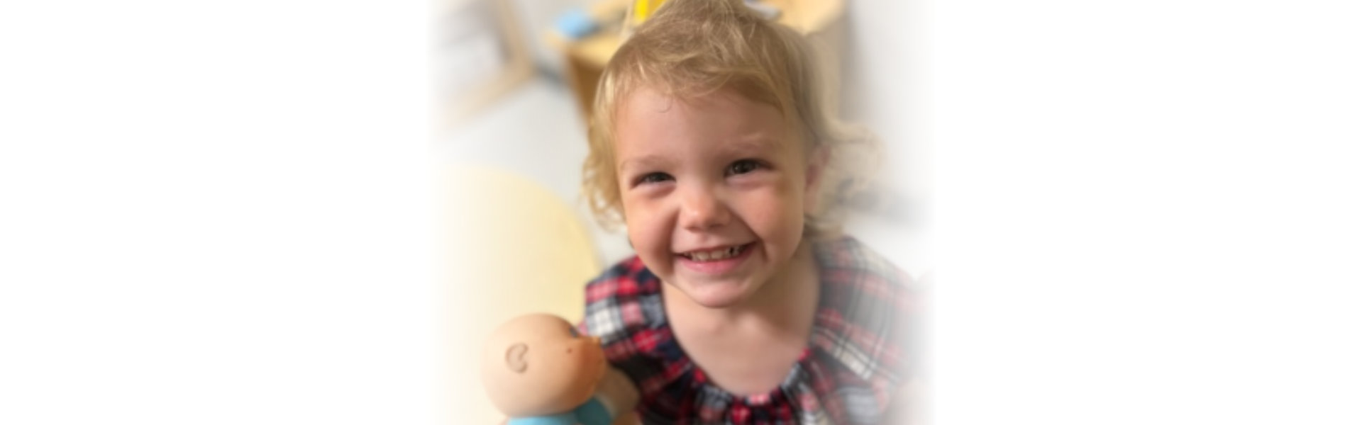 child smiling with a doll